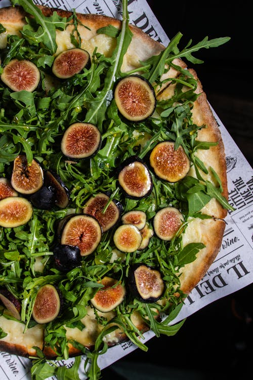 A pizza with figs and arugula on top