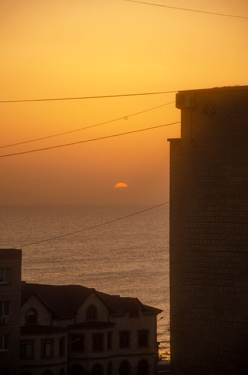Free Golden sunset over ocean with urban silhouette and serene seaside view. Stock Photo