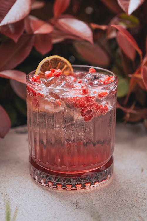 A cocktail with raspberry garnish sitting on a table