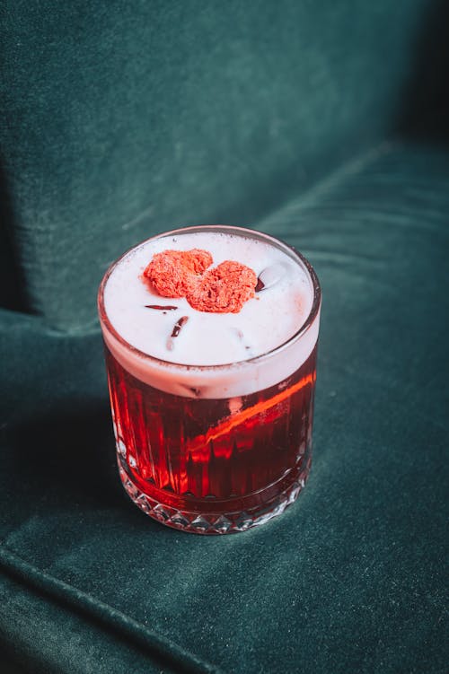 A cocktail with raspberry and mint on top