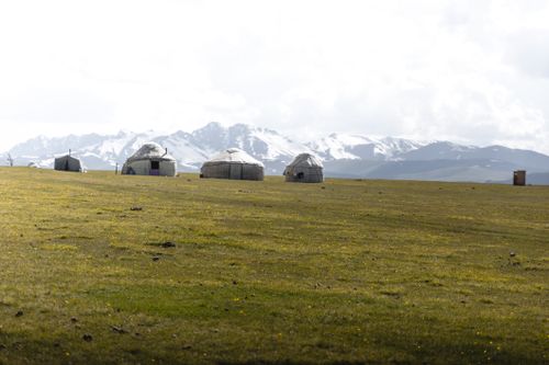 Free Traditional yurts in a mountain landscape under clear skies. Perfect outdoor adventure setting. Stock Photo