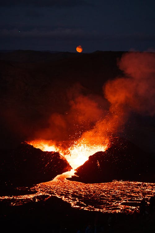 The moon rises over the lava flow at night