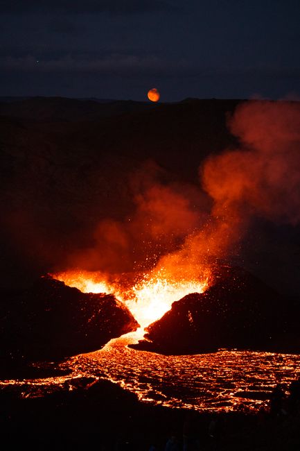 Captivating shot of lava flowing from a volcano at night under a full moon, depicting nature's fiery power.
