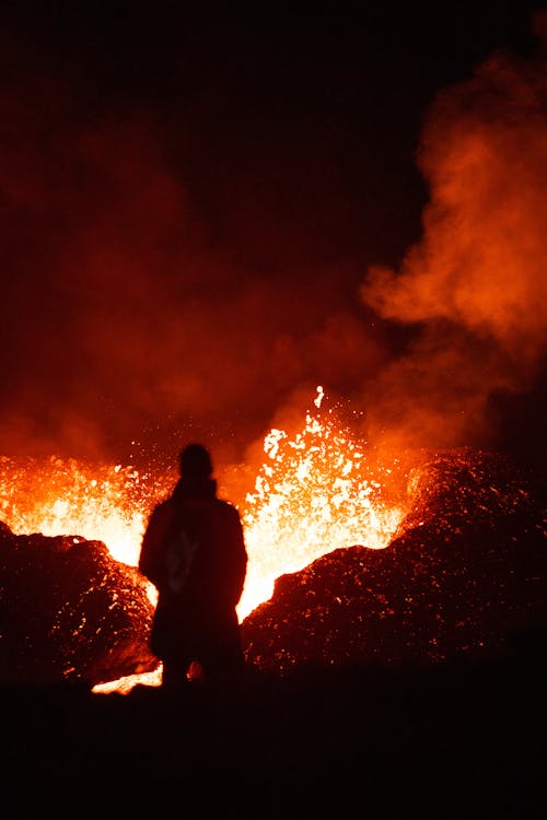 A person standing in front of a large lava flow