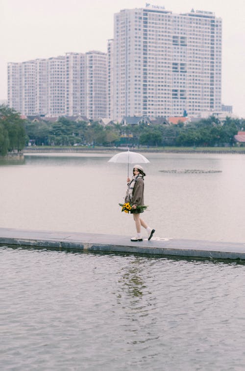 A woman walking across a lake with an umbrella