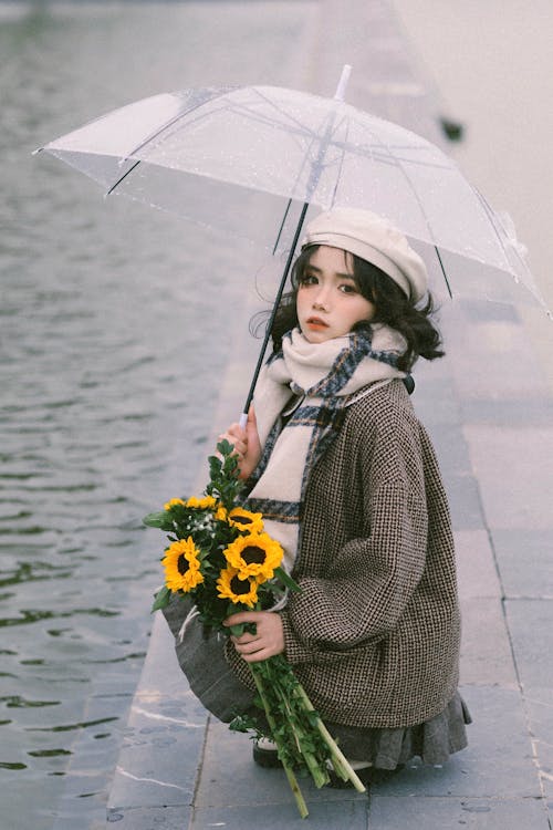 A woman holding a sunflower and an umbrella