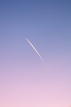 Jet plane contrail under a pink sunset sky over VDNH, Moscow. Atmospheric vertical shot.