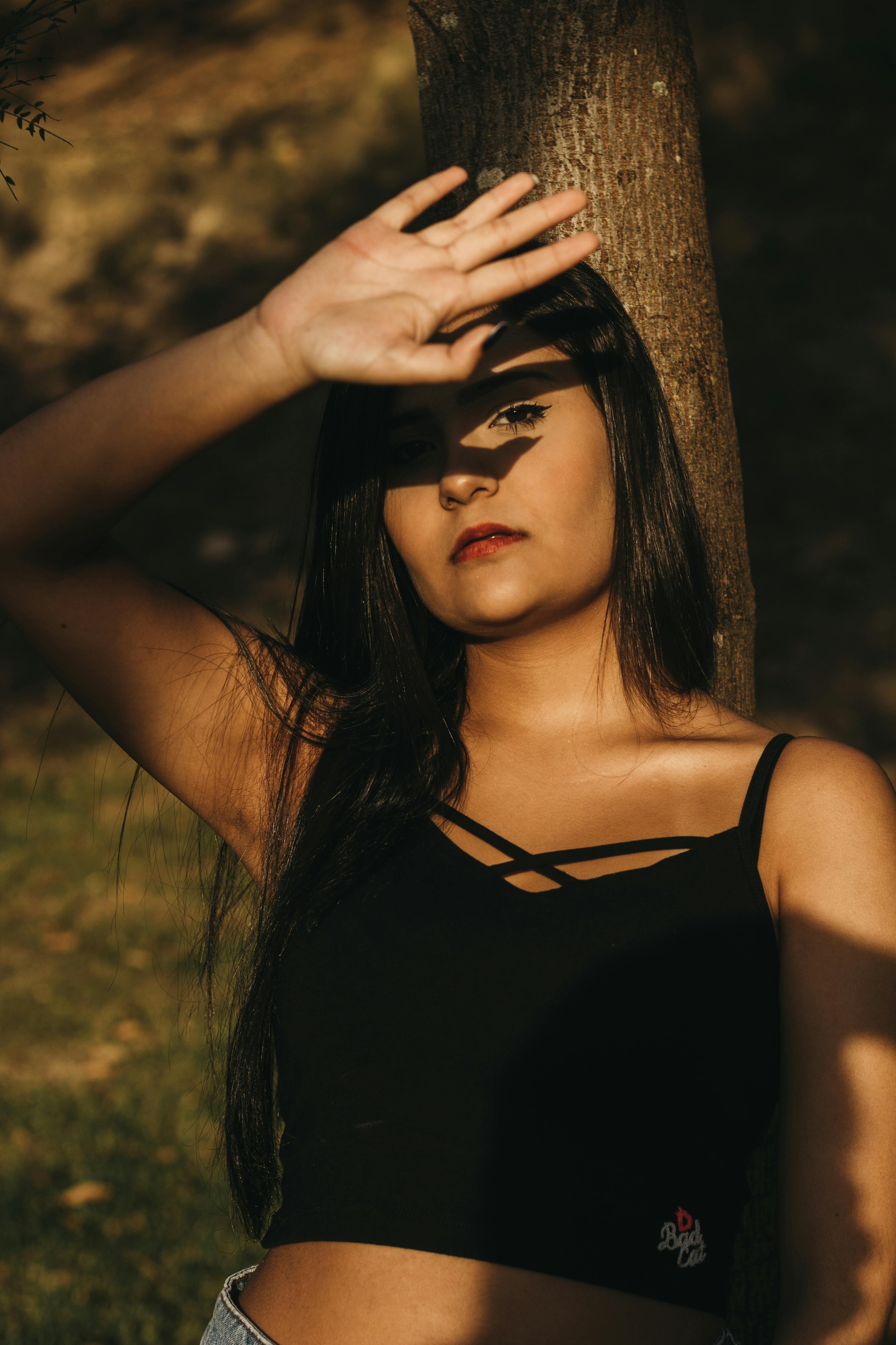 Photo of Woman Wearing Black Top Leaning on Tree