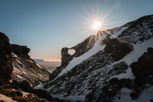 Capture of the sun shining over snow-covered rocky mountains in Hveragerði, Iceland.