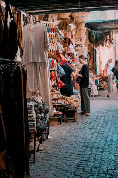 A woman is walking through a market with clothes