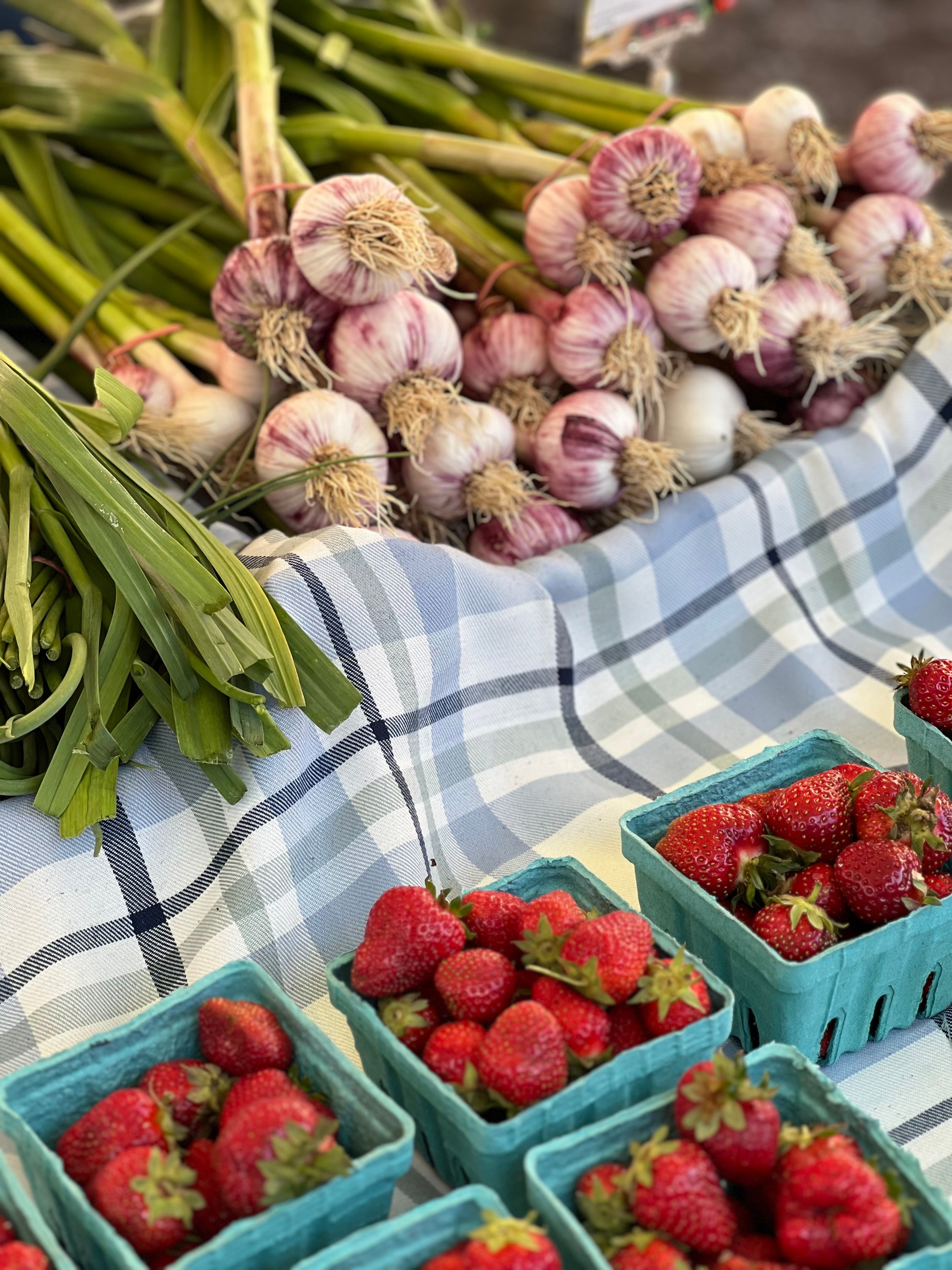 Vibrant strawberries and garlic displayed at a market stall, perfect for fresh produce lovers.. vibrant, strawberries, garlic