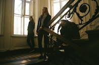 三位女士在华丽的室内楼梯上摆出姿势，营造出戏剧性且复古的氛围