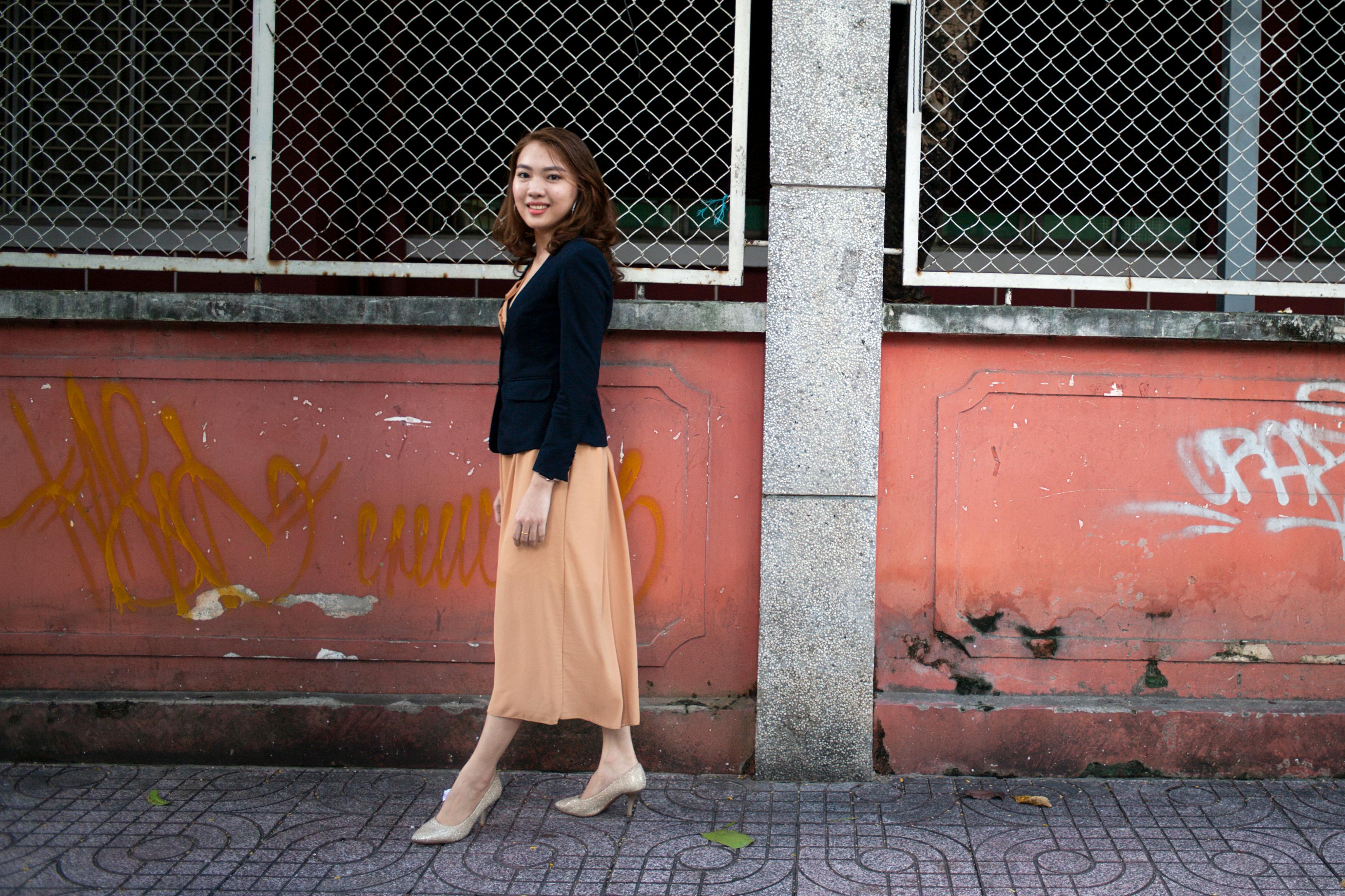 一名亚洲妇女自信地走过城市环境中涂鸦覆盖的墙壁