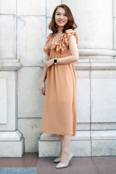 一位亚洲女子身着别致礼服，在石墙前摆出优雅姿态，尽显风格