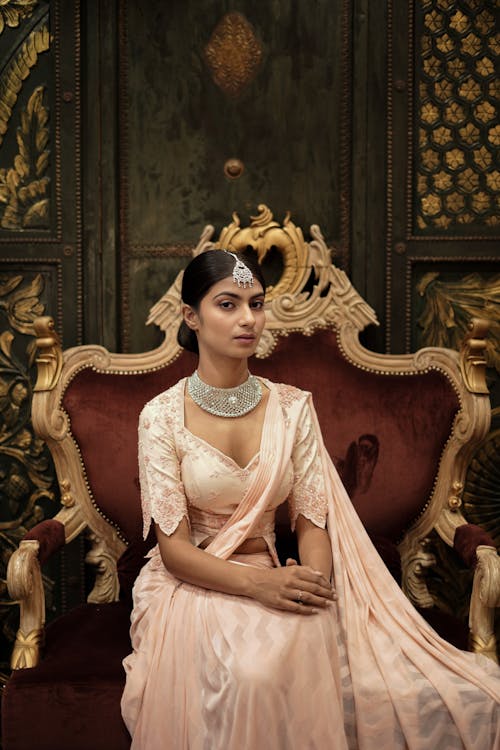 A woman in a pink sari sitting on a red chair