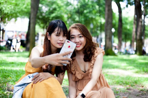 Photo of Two Woman Taking Selfie While Sitting on Grass