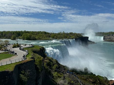 Stunning aerial shot of Niagara Falls, showcasing powerful waterfalls and lush greenery in spring.