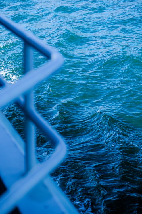 Free Close-up view of waves and a boat railing, showcasing vibrant ocean blues. Stock Photo