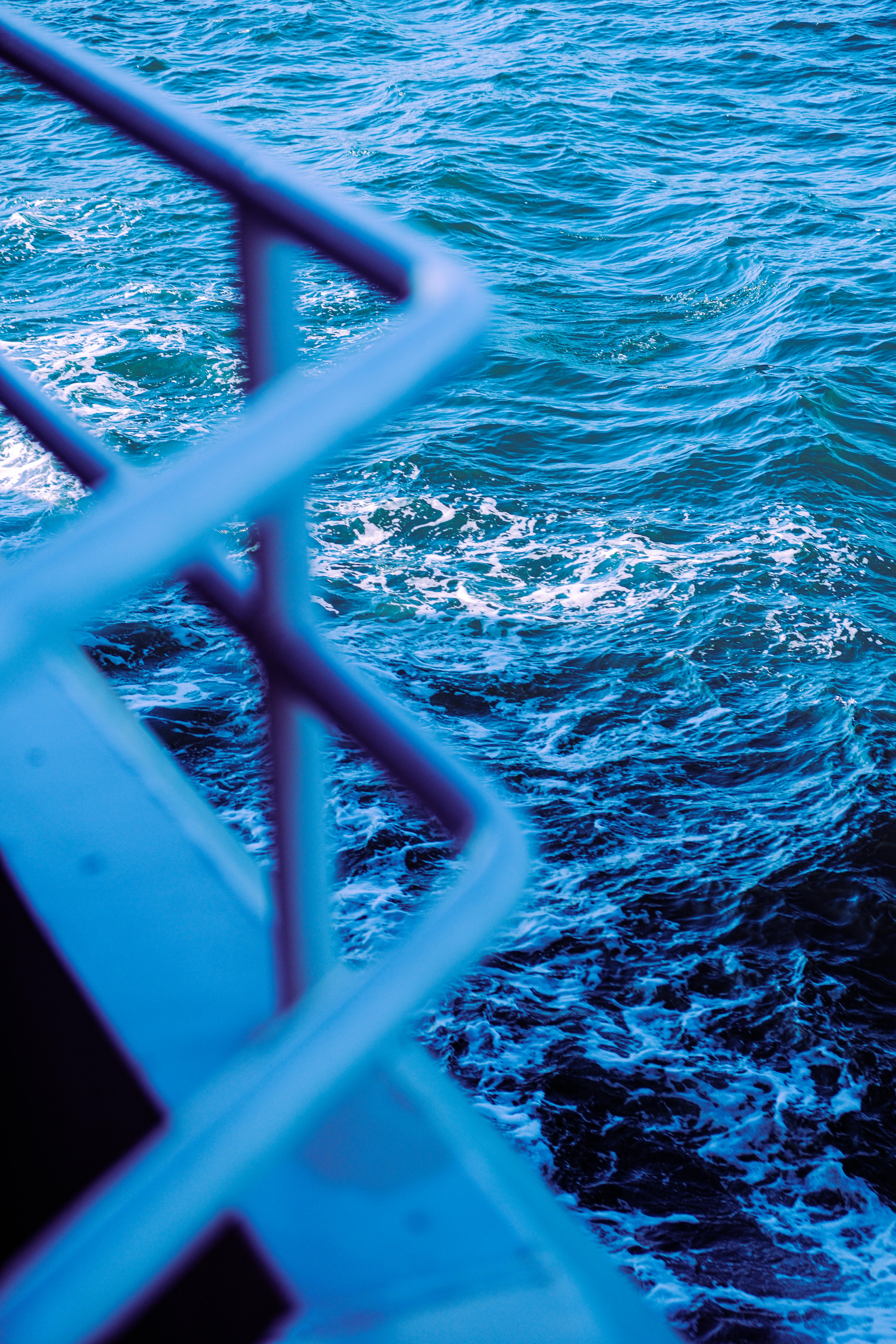 A vibrant blue ocean waves scene viewed from a railing, offering a splash of nature's beauty.