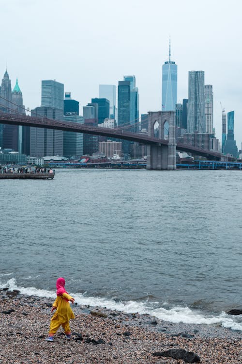 A person in a yellow raincoat walking on the beach