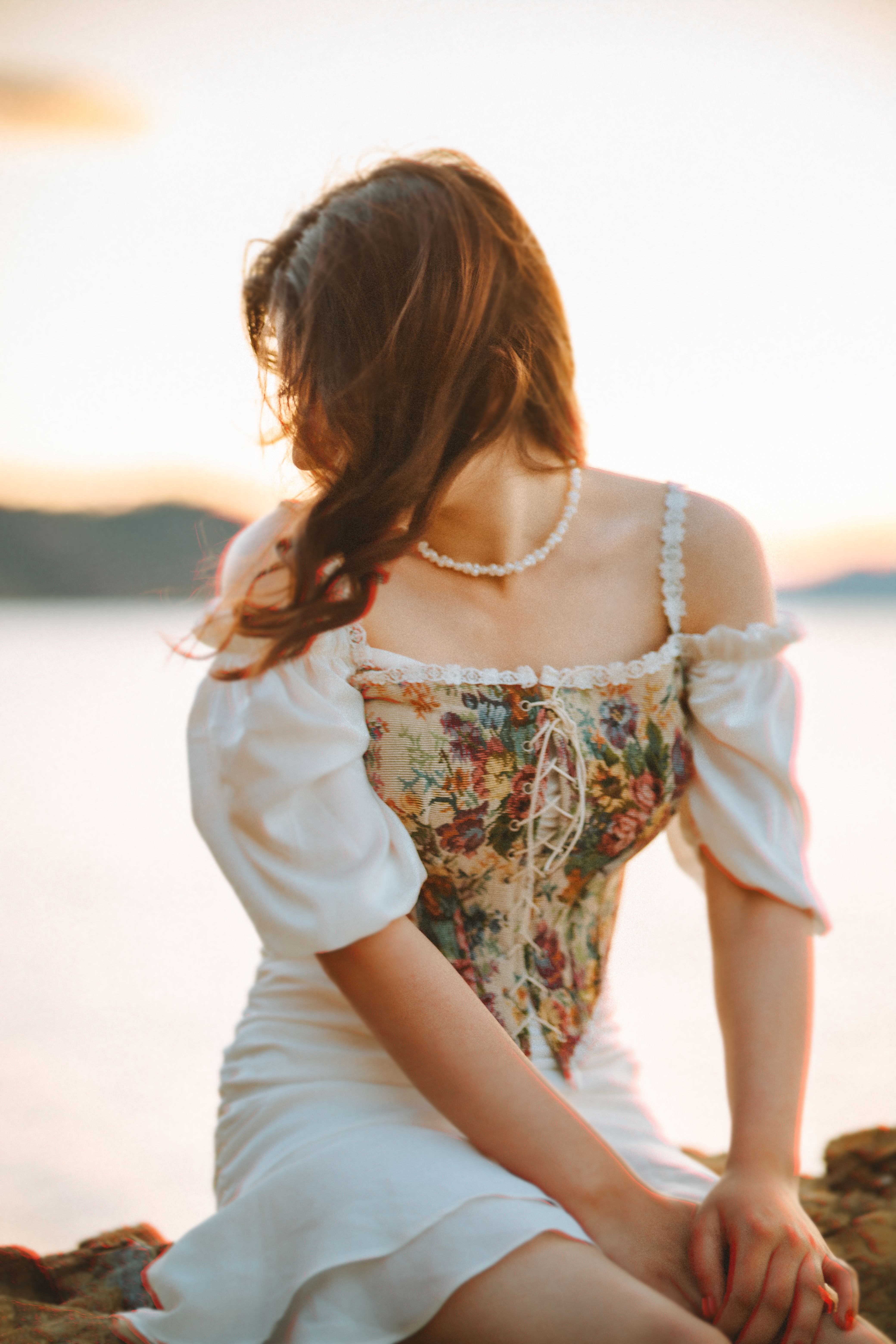Woman in White Dress with Floral Bodice Sitting by the Sea · Free Stock ...
