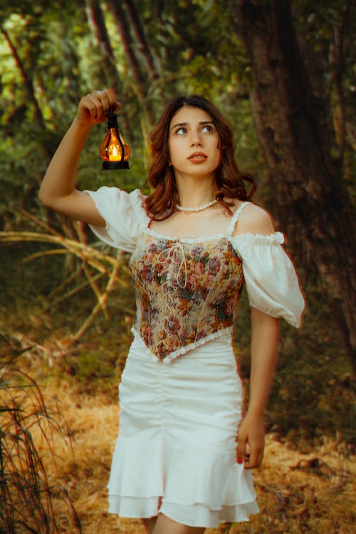 A woman in a white dress holding a lantern