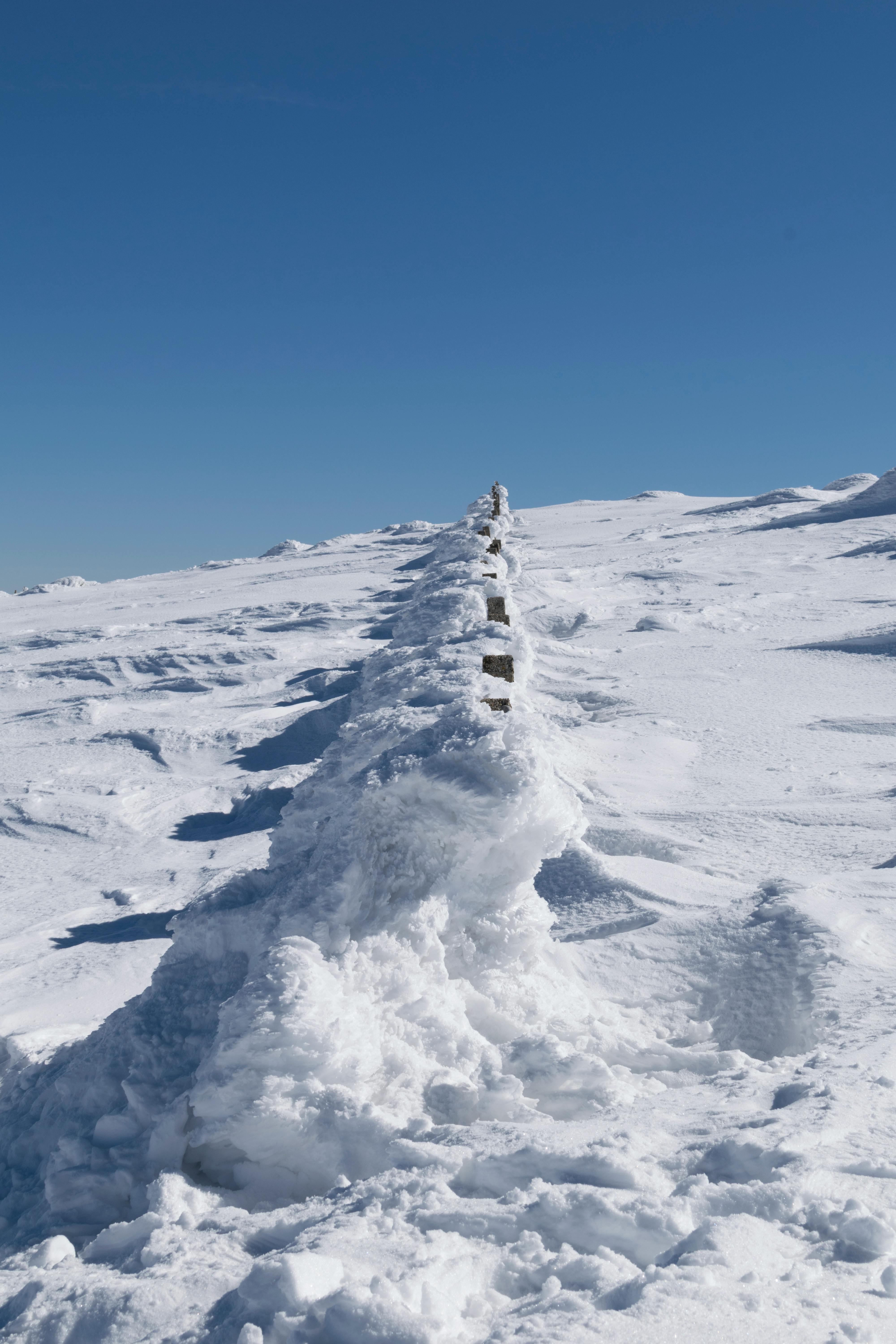A serene winter scene featuring a snow-covered mountain under a clear blue sky, perfect for nature enthusiasts.