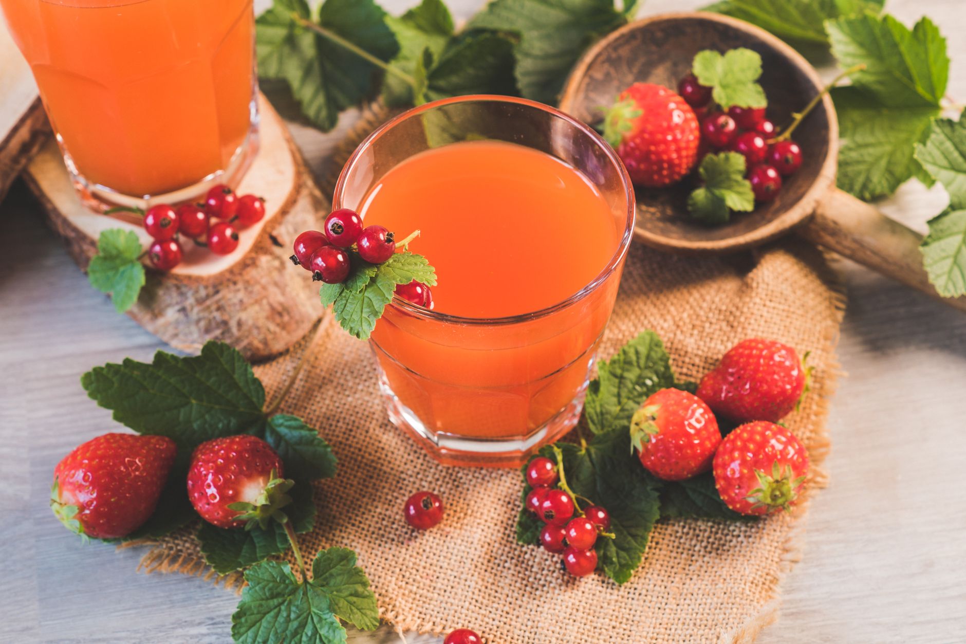 Tall glasses of fresh Strawberry OJ garnished with orange wheels
