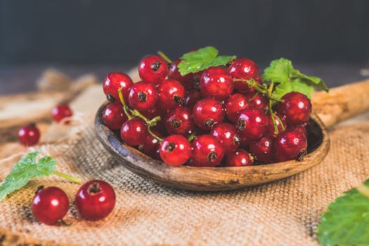 Close-up of juicy red currants on a wooden spoon, showcasing their freshness and vibrant color.