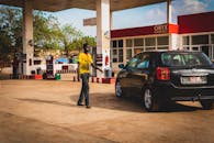 一名男子在明亮的日光下，于加油站为一辆黑色汽车加油