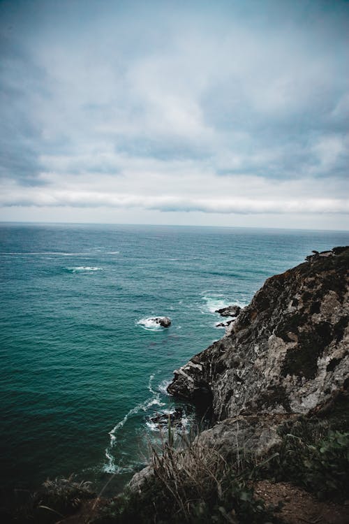 Free Black and Gray Cliff Towards Body of Water Stock Photo