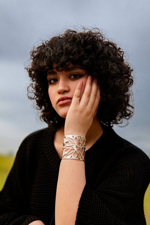 A woman with curly hair and a bracelet on her wrist