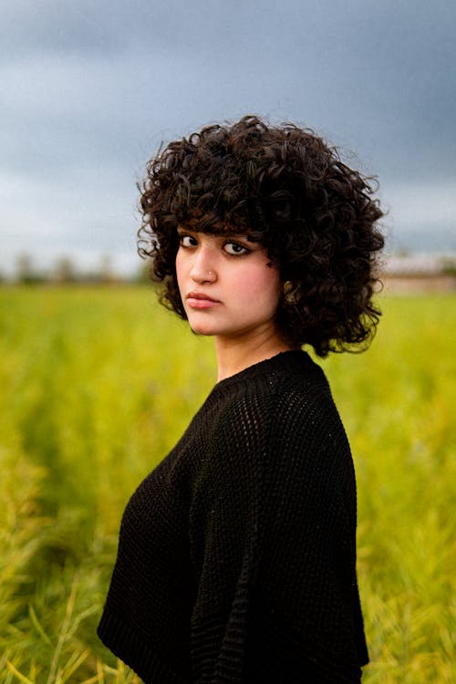 A woman with curly hair standing in a field
