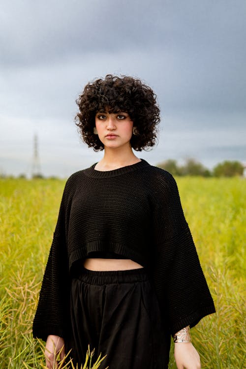 A woman with curly hair standing in a field