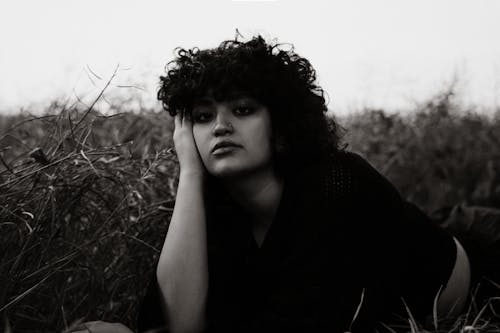 A woman with curly hair sitting in a field