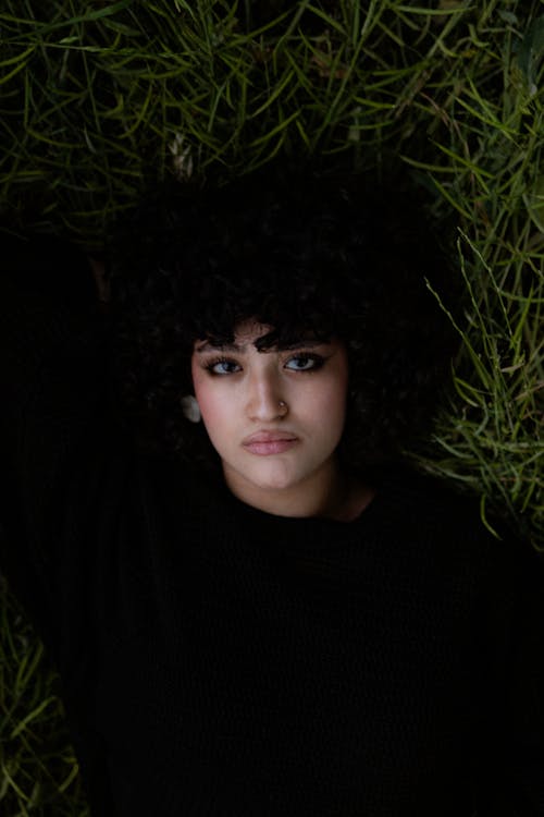 A woman with curly hair laying in the grass