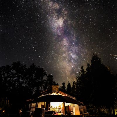 Lit cabin under a night sky surrounded by trees — photo by Nathan Moore on Pexels
