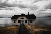 宁静的湖边船屋旁，有一条金属栏杆通道，上方是戏剧性的云层