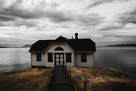 宁静的湖边船屋旁，有一条金属栏杆通道，上方是戏剧性的云层