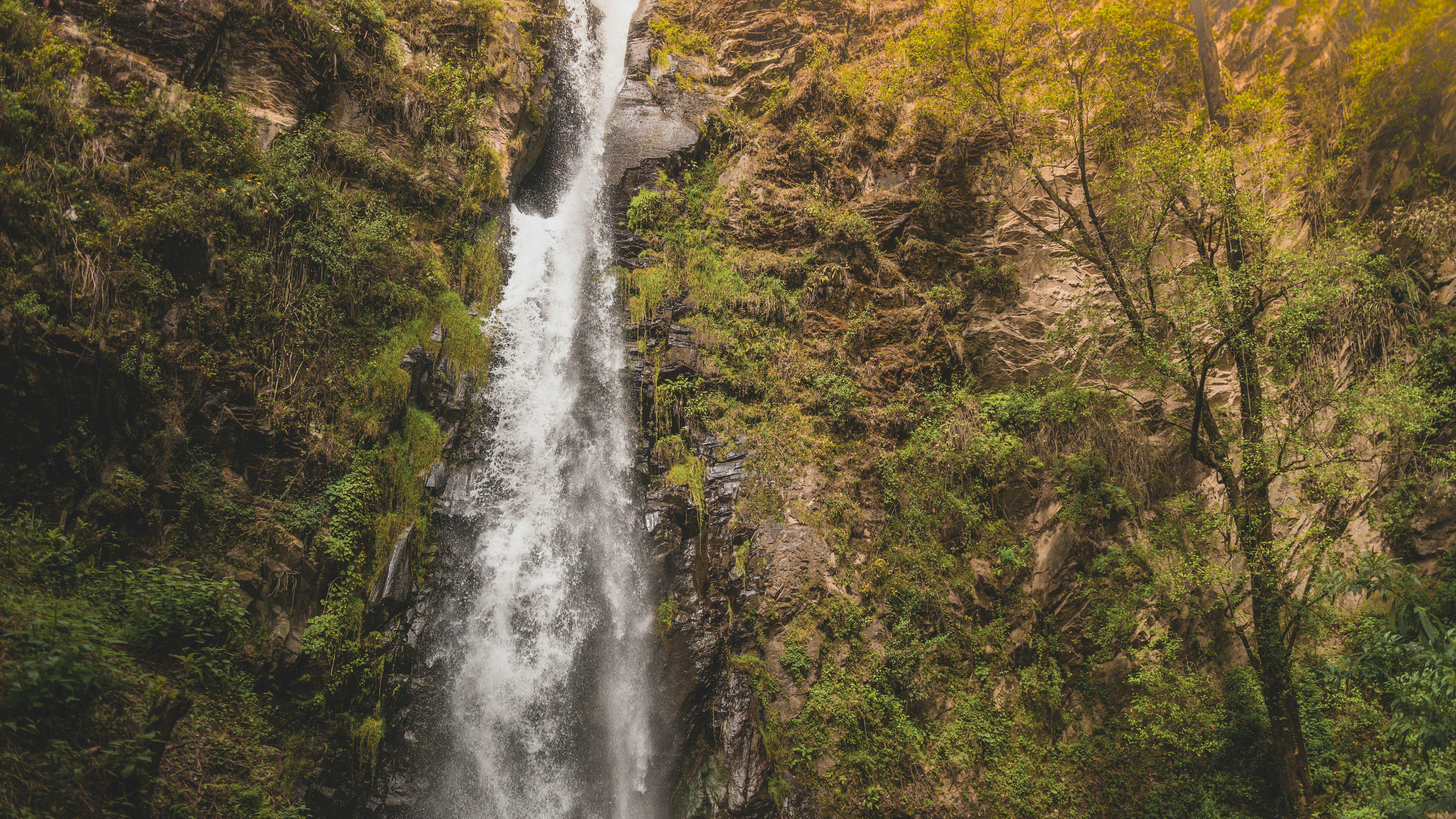 在宁静的户外环境中，壮丽的瀑布沿着郁郁葱葱的绿色悬崖边层层叠落