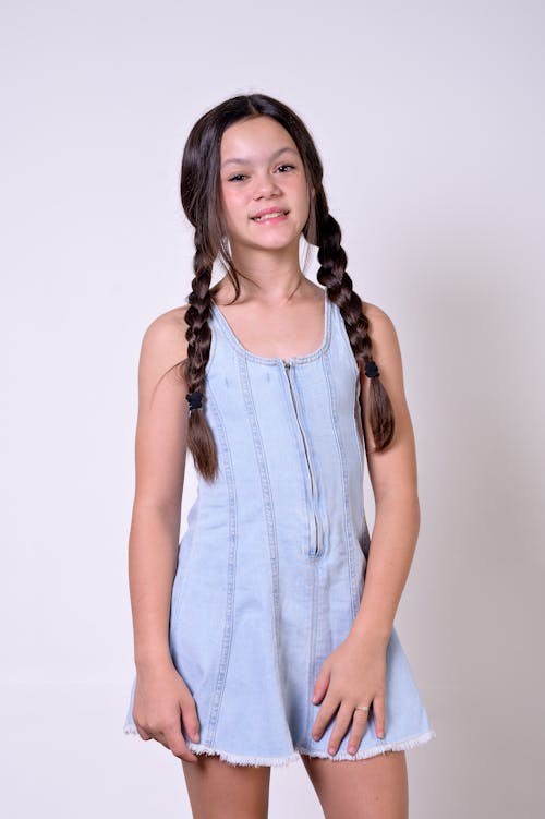 A young girl in a denim romper with braids