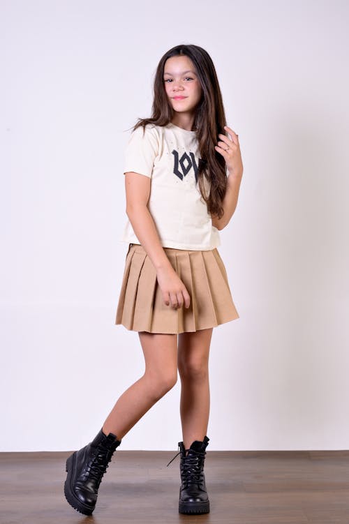 A girl in a skirt and boots posing for a photo