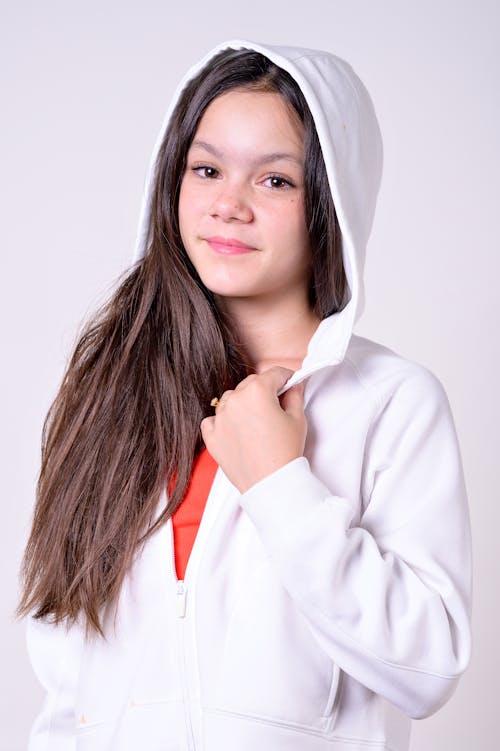 A young girl in a white hoodie and orange shirt