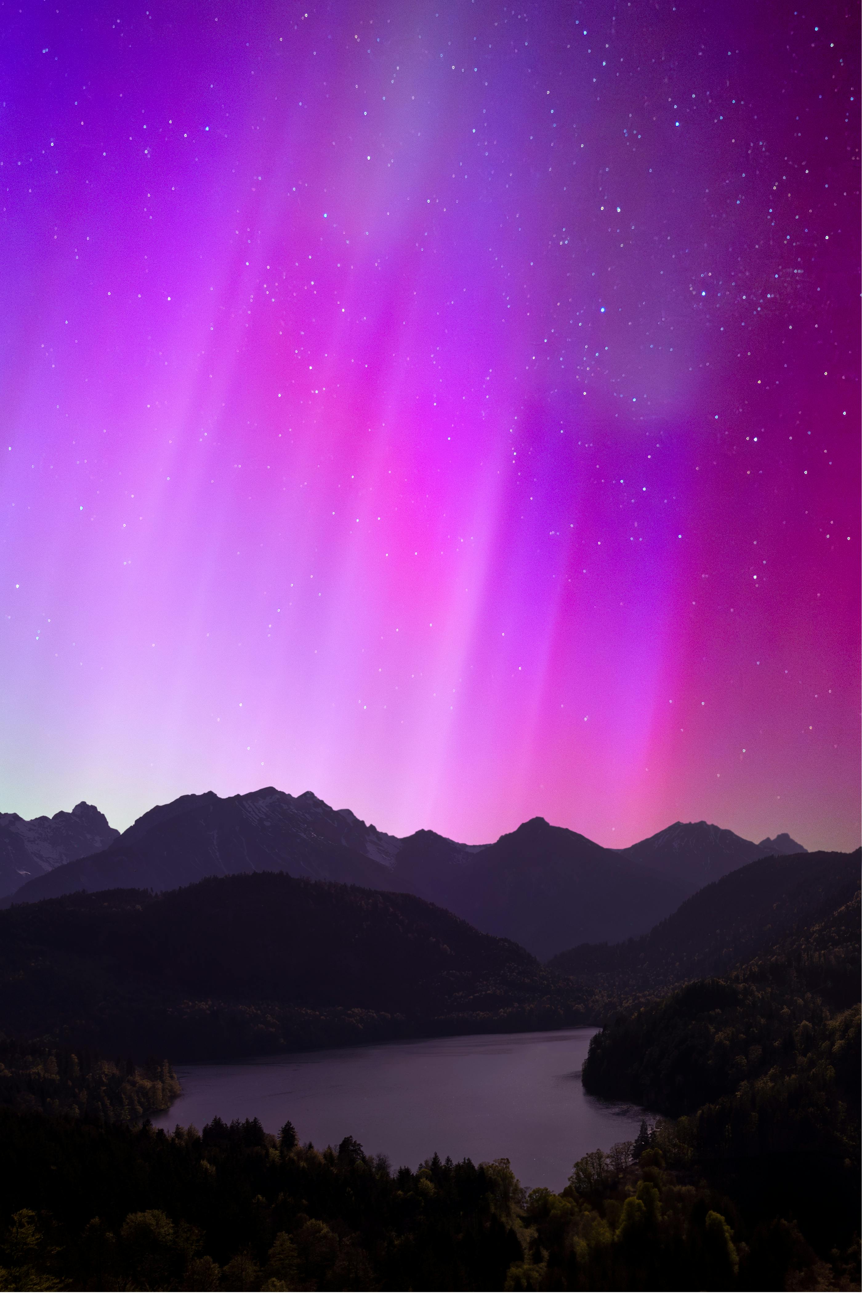 Breathtaking view of the aurora borealis illuminating the night sky over a serene mountain lake.