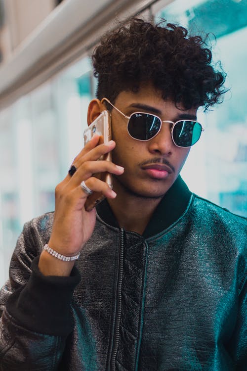 Free Photo of a Man Wearing a Black Bomber Jacket Using a Smartphone Stock Photo