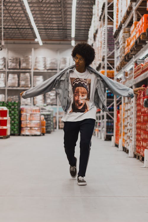 Photo of Man Walking Down Supermarket Aisle with His Hands Stretched