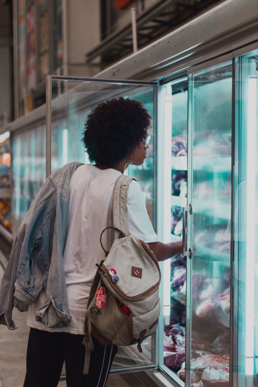 Shopper selecting frozen goods in a supermarket freezer aisle