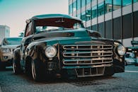 一辆经典的黑色老爷车停在城市街道上，展现出永恒的汽车优雅