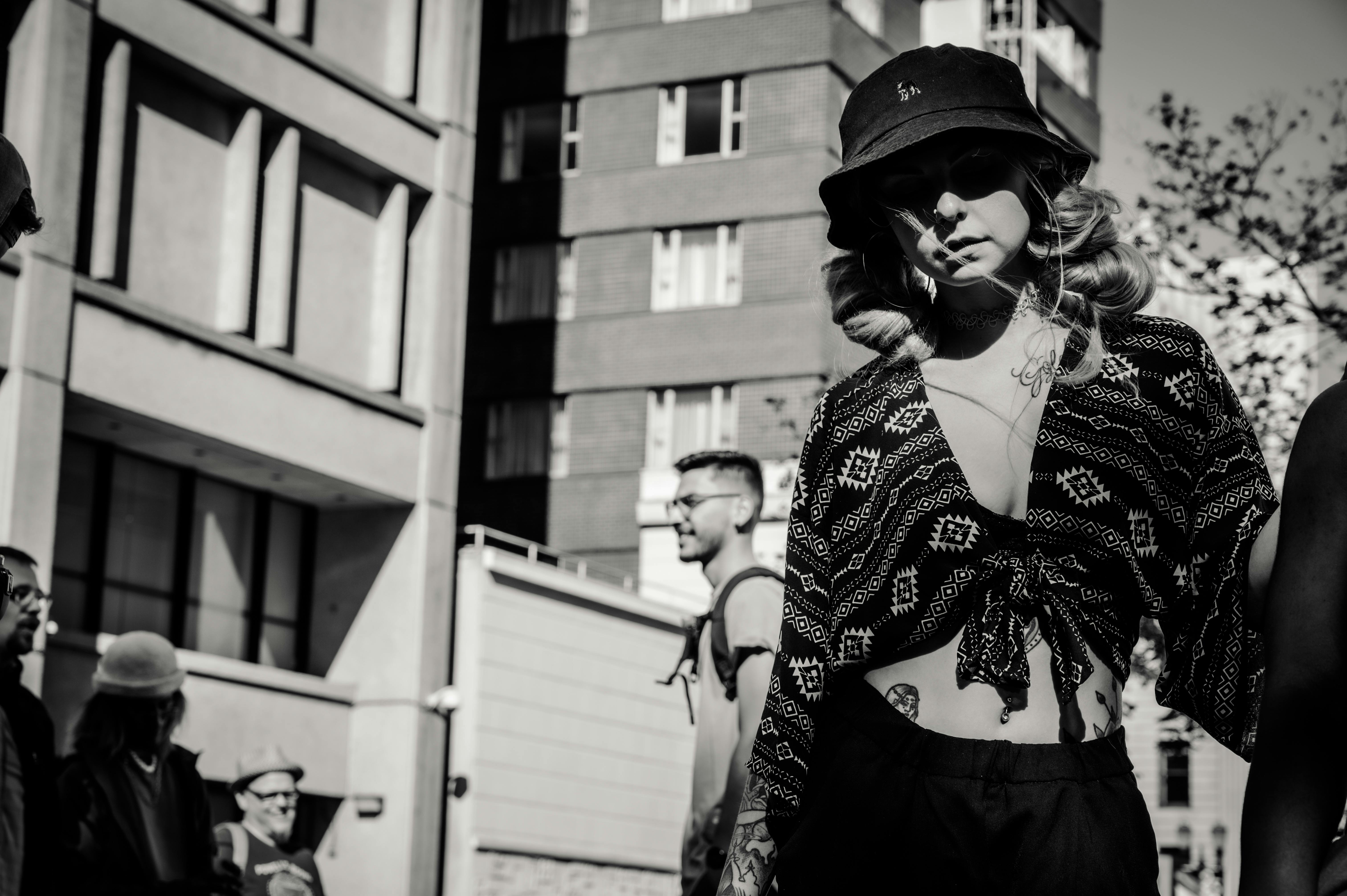 Stylish woman wearing patterned outfit and sunglasses in a black and white urban setting.