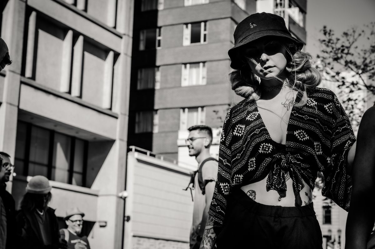 Stylish woman wearing patterned outfit and sunglasses in a black and white urban setting.